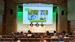 auditori del fòrum, dos homes i una dona amb taula presidencial parlant sobre la nova edició de la convocatòria d'impuls pel territori